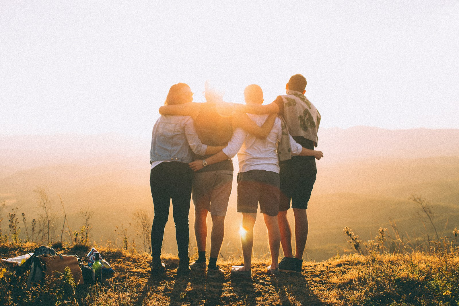 Planning a Family Vacation to Tanzania? Here’s What You Need to Know 3 four person hands wrap around shoulders while looking at sunset